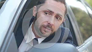 Close-up angry male young driver leaning out car window shouting gesturing looking away. Portrait of dissatisfied