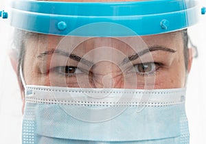 Close-up of angry woman eyes wearing medical mask and face screen