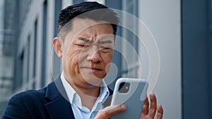 Close up angry worried stressed Asian middle-aged 40s man user businessman employer entrepreneur trying browsing on