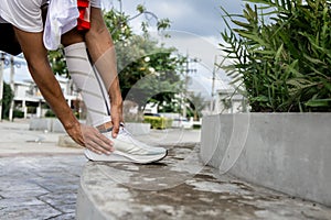Close Up on Ankle Injury. The man use hands hold on his ankle while running in the park. space for text or design