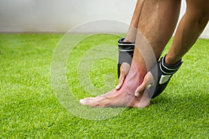 Close Up on Ankle Injury. The man use hands hold on his ankle while running in the park. space for text or design. highlight on