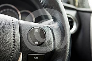Close up of the answer and reject phone buttons on the steering wheel with black leather cover in a car.