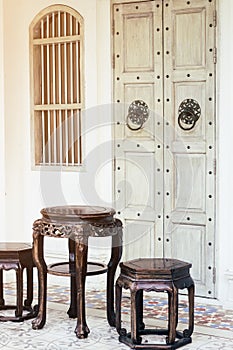 Close up antique chinese traditional chairs and table with white Chino-Portuguese door background. Asia architecture vintage style