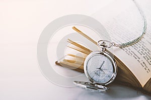 Close up of antique silver pocket watch and opened book