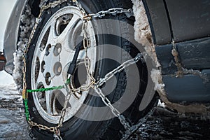 Close-up of antislip chain on car wheel with friction tire. Bottom perspective. The concept of safety on snowy roads. photo