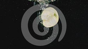 Close up of an apple half thrown in the water isolated on black background. Action. Green apple in transparent water