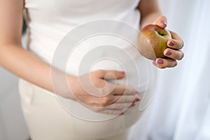 Close up apple in pregnant womans hand. Diet, fruits and vitamins during pregnancy