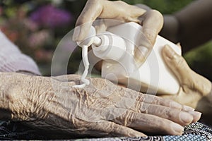 Close up applying cream on women old hands to moisturize the skin