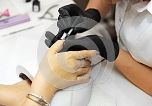 Close-up applying nail polish to female nail in salon. Woman hand with purple nailpolish after the manicure.