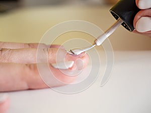 Close-up of applying white nail polish with a brush. Manicure at home. Poor-quality manicure