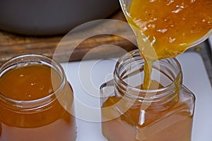 Close up of apricot jam being poured into a glass jar
