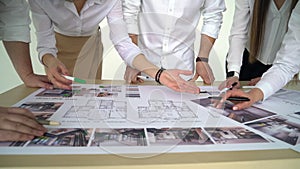 Close Up Of Architects Discussing Plan Together At Desk With Blueprints