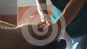 Close up arms of professional masseur doing slowly rubdown leg of athlete lying on massage table in salon. Male hands of