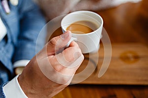 Close up of arms of successful business having a business meeting with his client in cafe. The man in suit is drinking coffee. Mor