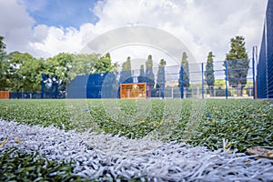Close-up of the artificial grass of a soccer field With the goal out of focus in the background