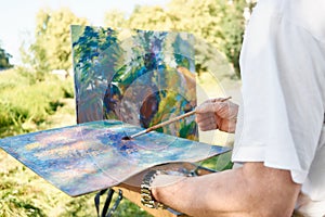 Close-up of artist hand holding painting brush and palette of colors.