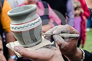 Close-up on artist hands personalizing a clay jug by writing the name of a person. photo