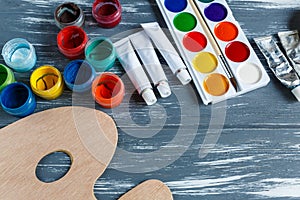 Close up of artist paint brushes, palette and watercolors on grunge gray wooden background.