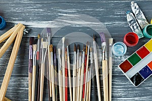 Close up of artist paint brushes, palette and watercolors on grunge gray wooden background. Set of multicolored paints