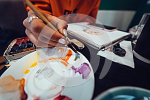 Close up of artist with palette, paint brush and easel painting at studio