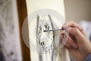 Close Up Of Artist Sitting At Easel Drawing Picture Of Dog In Charcoal