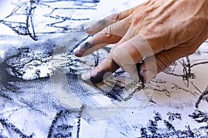 Close up of artists hand painting with graphite crayon