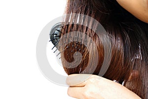 Close up Asia woman wear white shirt make hair color treatments hard combing her hairs on white background.