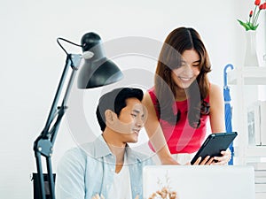 Close-up Asian business couple, young man and woman, colleagues using tablet and laptop computer.