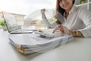 Close up Asian business woman using calculator to calculate tax and financial data of business at office