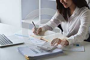 Close up Asian business woman using calculator to calculate tax and financial data of business at office