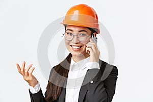 Close-up of asian businesswoman manage enterprise, engineer in safety helmet and suit having phone conversation, calling