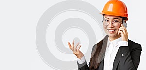 Close-up of asian businesswoman manage enterprise, engineer in safety helmet and suit having phone conversation, calling