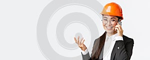 Close-up of asian businesswoman manage enterprise, engineer in safety helmet and suit having phone conversation, calling