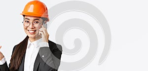 Close-up of asian businesswoman manage enterprise, engineer in safety helmet and suit having phone conversation, calling