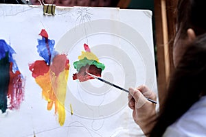 Close up of Asian child girl is painting on white paper.