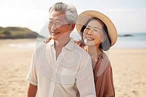 close up of asian elderly carefree couple standing on the beach and smiling at you happily in sunset background