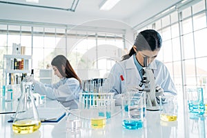 Close up of Asian female scientist research team in protective gear using microscope in the laboratory