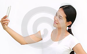 Close up asian girl taking pictures of herself through cell phone on white background
