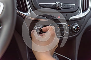 Close-up Asian left male hand turning knob button temperature adjust air conditioner to 64 F degree