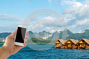 Close up of Asian Male Hand Holding Smart Mobile Phone with Blank Screen on Sea, Blue Sky and Luxury Floating Hotel while Travel