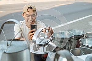 Close up of asian male seller squat using phone camera when taking photo a kettles