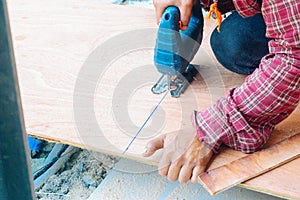 Close up Asian man carpenter using electric saws to cut large board of wood in a construction site. Male worker sawing board. Craf