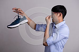 Close up asian man holding dirty stinky shoe with an expression of disgust. Healthcare concept