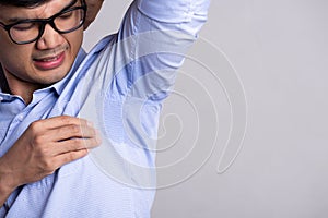 Close up asian man with hyperhidrosis sweating. Young asia man with sweat stain on his clothes against grey background. Healthcare