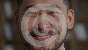 Close up of an Asian man opening eyes and smile while looking at camera in slow motion