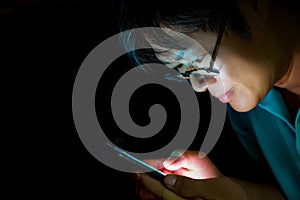 Close up Asian man wearing glasses watching on cellphone at night.