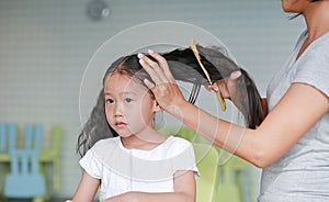 Close-up Asian mom combing her daughter hair at home