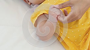 Close up of asian mother holding her newborn baby`s hand on the bed