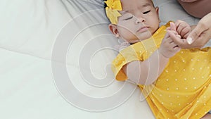 Close up of asian mother holding her newborn baby`s hand on the bed in the morning