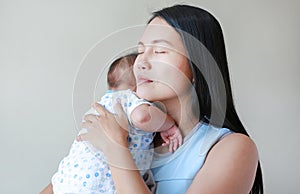 Close-up of Asian mother hugging her baby in the bedroom